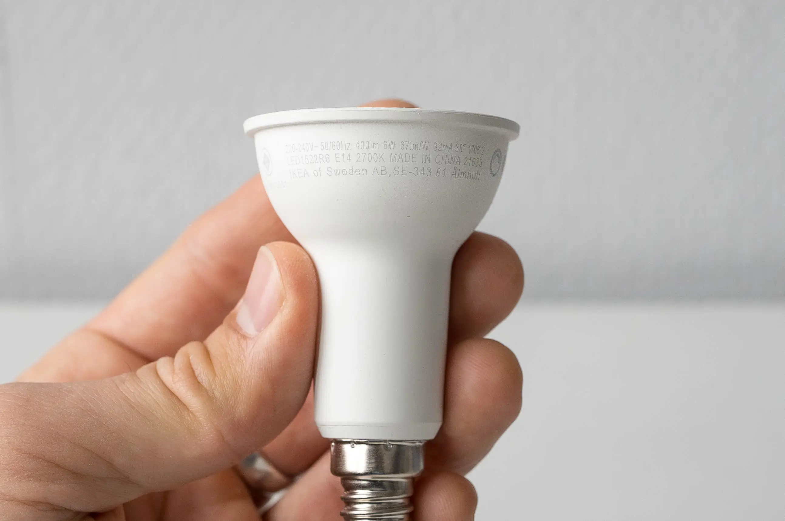 Close up shot of a lightbulb with an E14 thread, showing the description of the bulb containing wattage, lumen, volt, and the manufacturer.