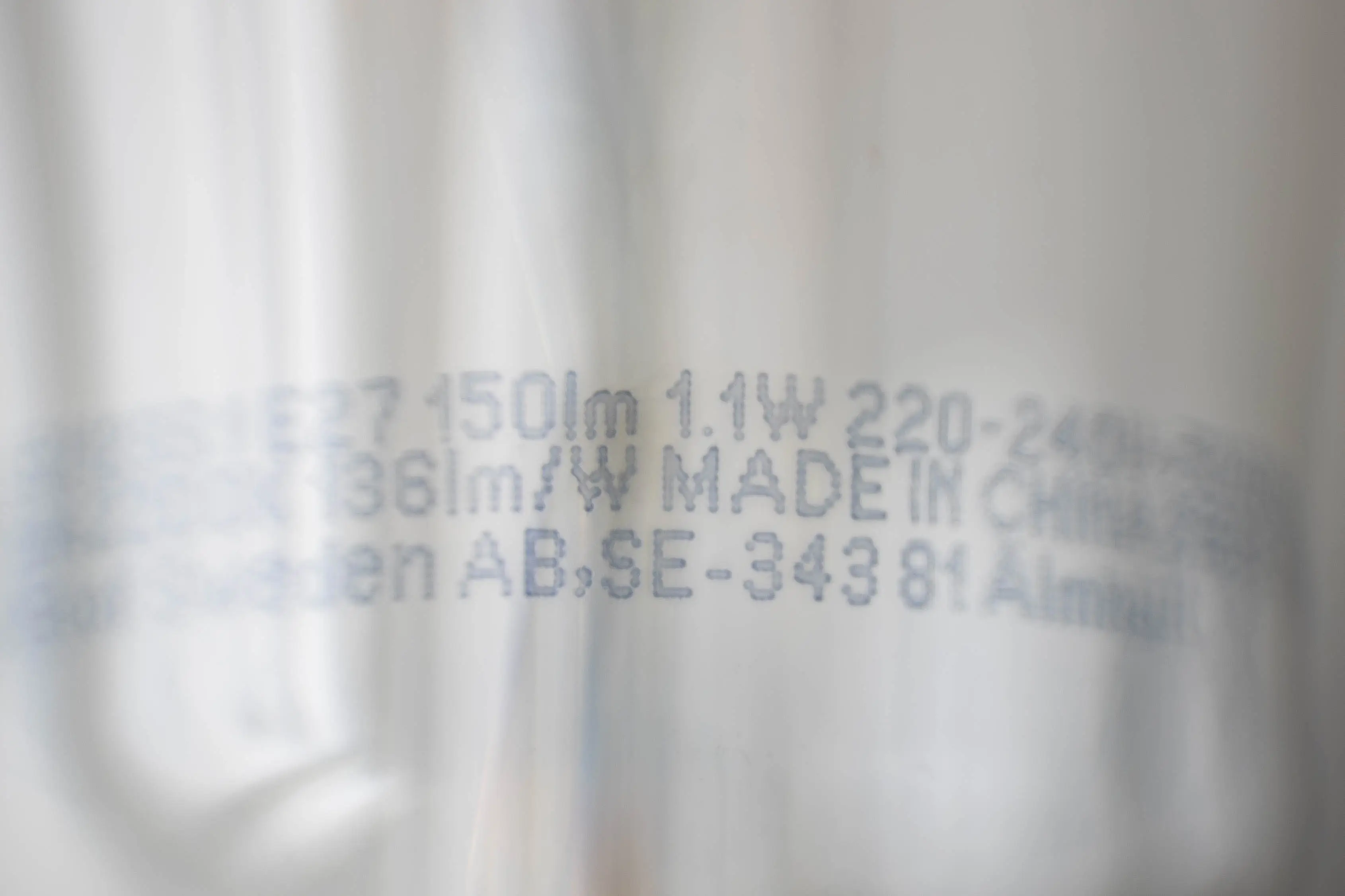 Macro shot of a lightbulb with an E27 thread, showing the close-up description of the bulb containing wattage, lumen and volt.
