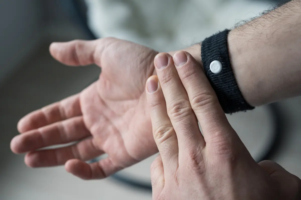 Sea sickness band on wrist with 3 fingers showing the P6 acupressure point