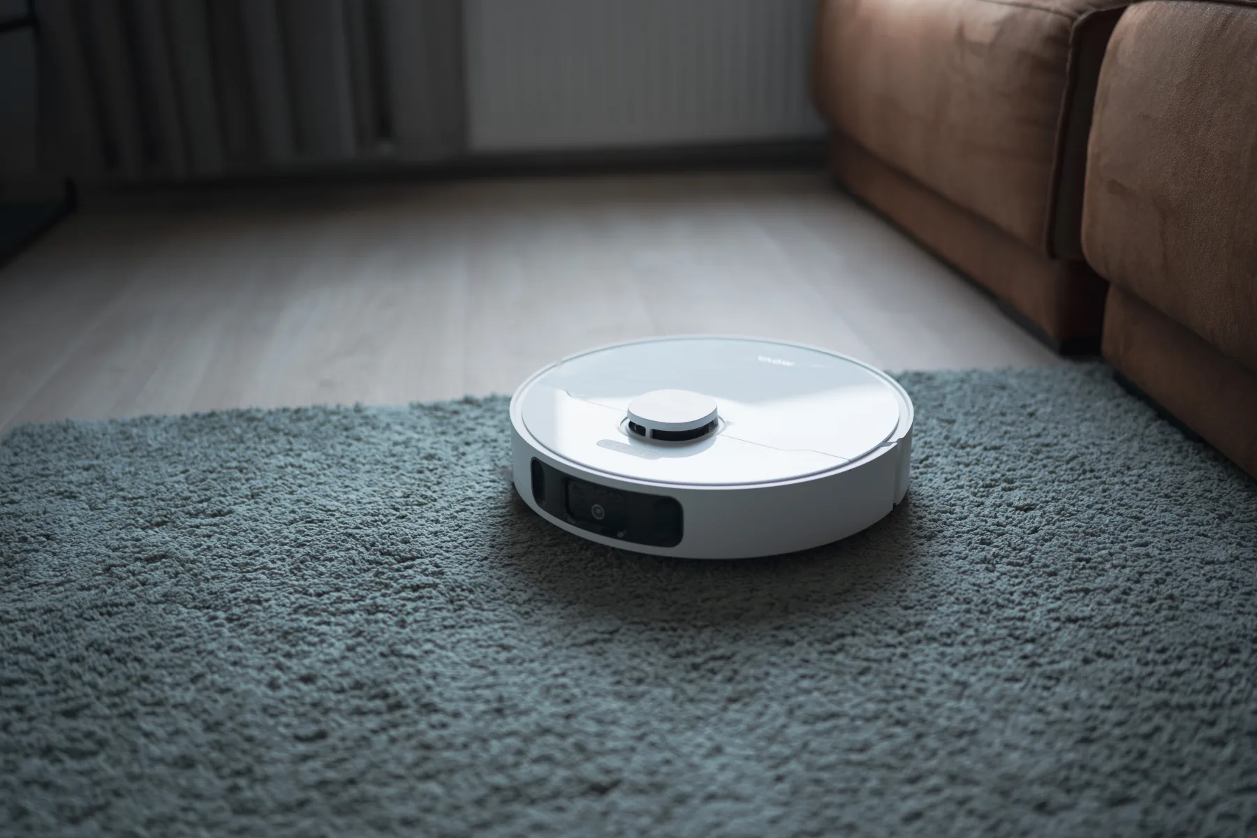 White robot vacuum cleaner on a carpet vacuuming.
